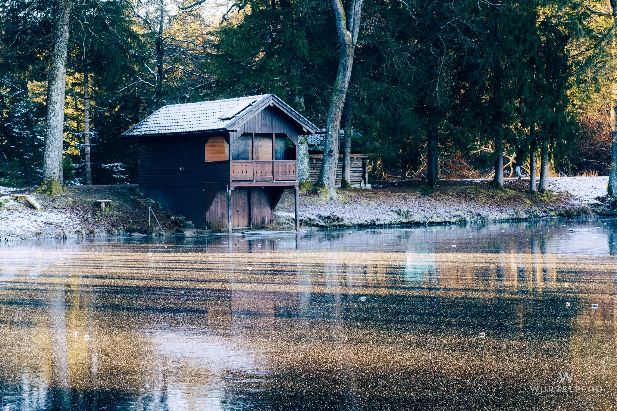 Wooden boathouse on frozen winter lake.